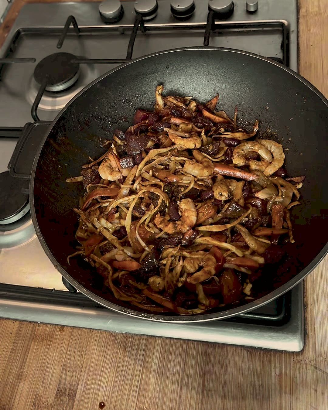 A wok of prawns and stir-fried vegetables on the hob in Pablo's kitchen.