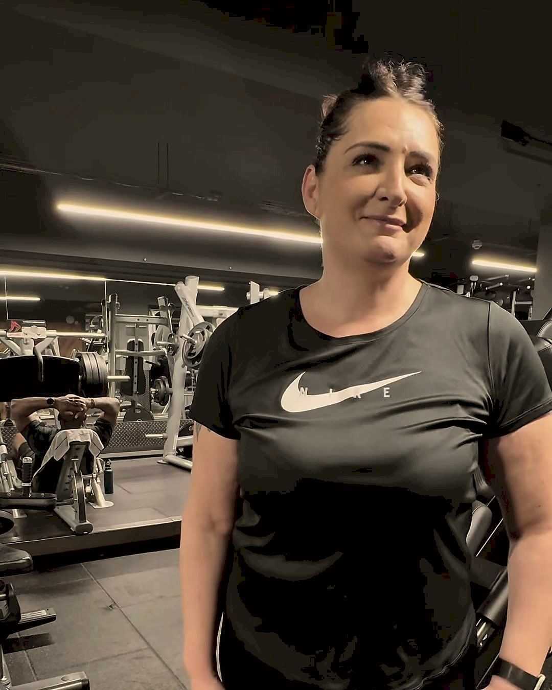 Mery smiling on the gym floor in a black training top.